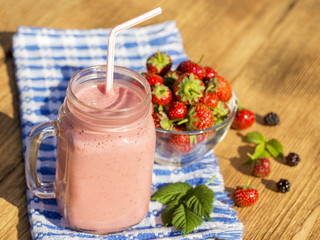 Strawberry, raspberries and banana juice smoothie shake in glass, outdoors, close up