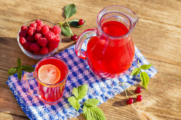 Dietary detox drink with lemon juice, red strawberry, cherry and raspberry in clear water with ice