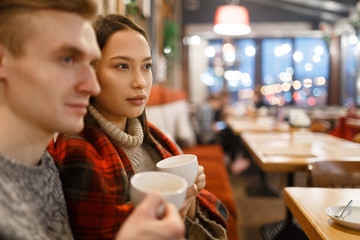 Young couple with cups of tea relaxing in cafeteria