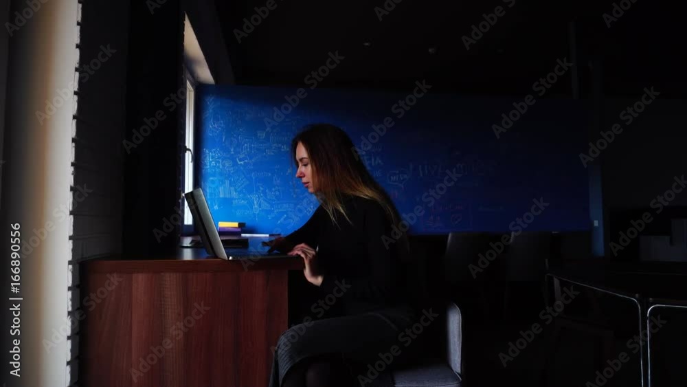 Wall mural nice successful student writes essay and types text on computer keyboard and sits at table in modern