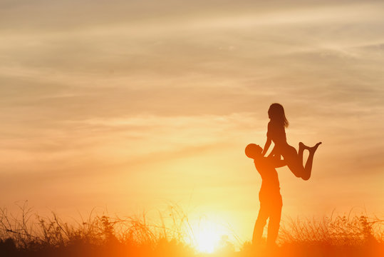 Silhouette of  happy young couple in love hugging enjoys in summer , Loving man holding on hands his woman together outdoors