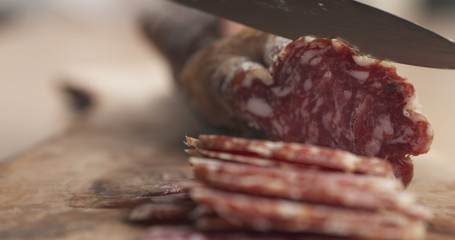 slicing dried italian salami on table