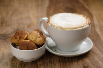 cappuccino with profiteroles on wood table