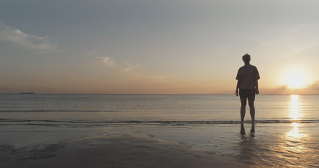 teen girl barefoot stand in water on baltic sea beach in sunset time