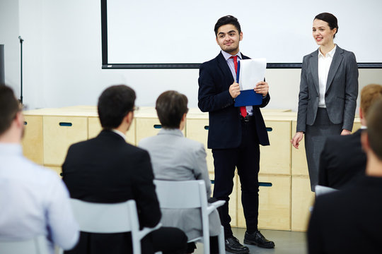 Two speakers carrying out business training by whiteboard in conference hall