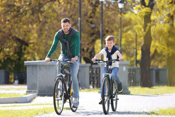 Obraz premium Dad and son riding bicycles outdoors
