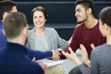 Psychological group attendants handshaking after talk while their colleagues applauding