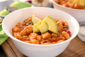 Bowl with delicious turkey chili on wooden board