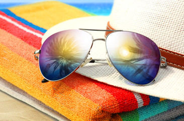 Sonnenbrille, Hut und Handtuch am Strand