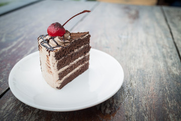 chocolate cake with cherry topping in cozy outdoor cafe