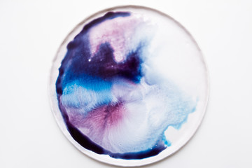 Abstract artistic image of colorful splash in motion on round plate. Watercolor gradient of dark blue to light purple on white background