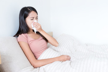 Sick Woman sneezing on bed