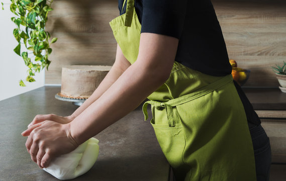 Unrecognisable woman preparing white fondant for cake decorating, hands detail