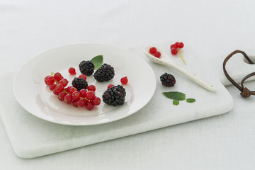 Red currant and blueberries on a white marble cutting board
