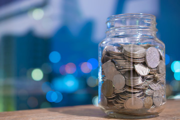 Various international currency coins in the mug with abstract bokeh background.