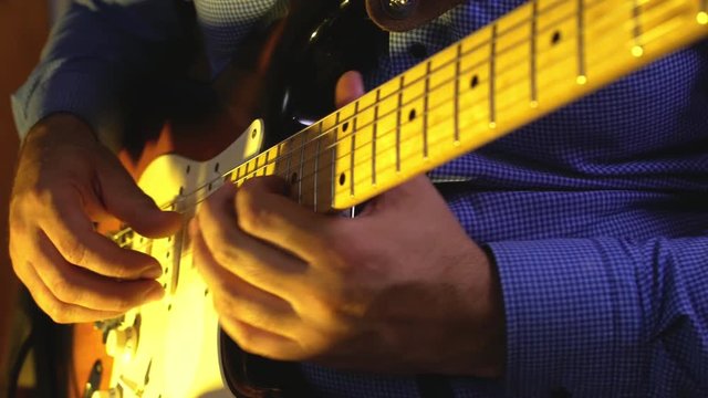 Musician plays heavy metal by electric guitar at the dark record studio close-up