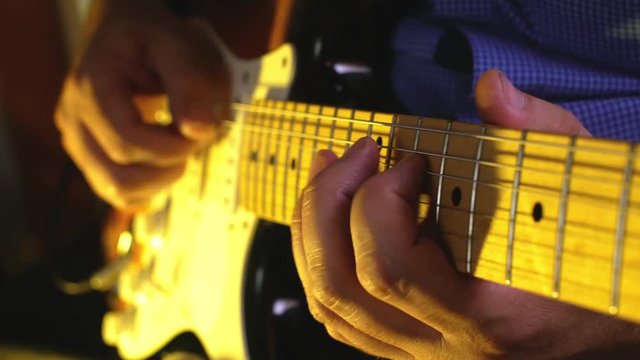 Musician plays hard rock by electric guitar at the club concert close-up