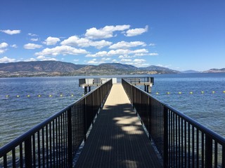 Fototapeta premium Lake pier in summertime with mountains and blue sky