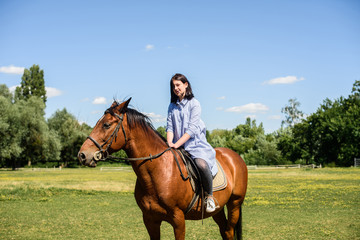 young beautiful brunette girl riding horse outdoor