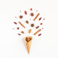 Autumn composition. Cinnamon sticks, anise star, pine cones, autumn leaves in waffle cone. Flat lay, top view, square