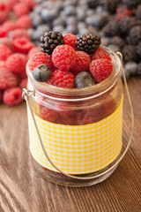 different berries in a basket on a wooden table