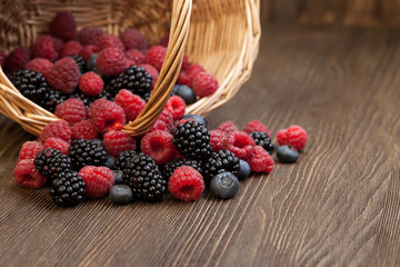 different berries in a basket on a wooden table