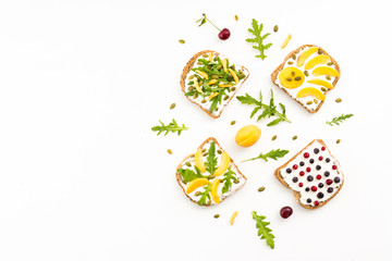 Healthy food. Breakfast with sandwiches, cherry, blueberries, nuts, soft cheese, toast, arugula, lettuce on white background. Top view, flat lay