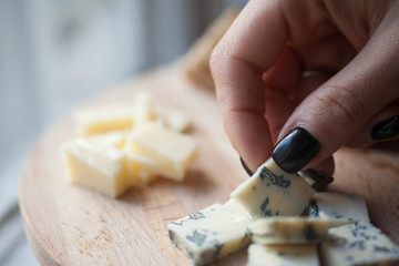 hands holding a piece of cheese DorBlu over the plate