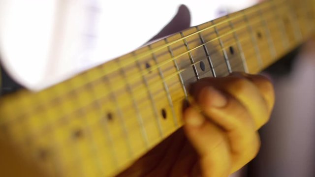 Guitarist plays heavy metal by electric guitar neck close-up