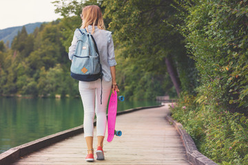 Attractive girl standing with her penny board outdoors. © Kitja