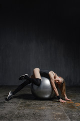 Young girl doing exercises with fit ball at studio