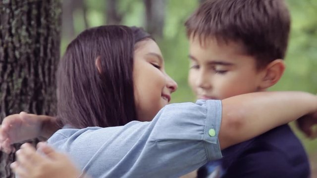 Portrait. A little boy is kissing with a little girl and hugging loving hard each other. Slow motion