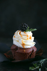 Chocolate capcake with vanilla cream and blackberries on a dark background