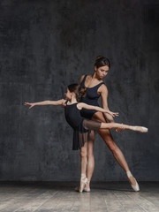 Young ballerina posing with the ballet teacher in studio