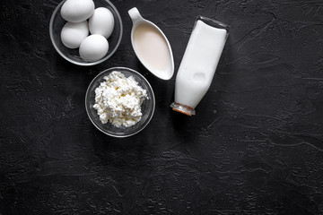 Healthy food. Milk, cottage, eggs on black stone background top view copyspace