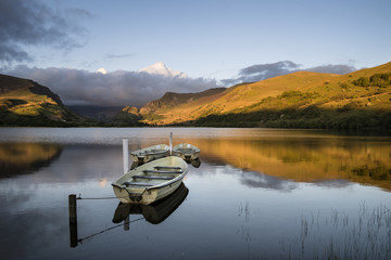 Stunning dramatic stormy sky formations over breathtaking mountain lake landscape with rowing boats...