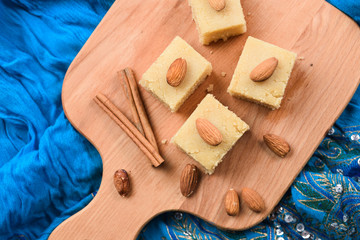 Homemade Indian sweets, halva wih cinnamon and almonds served on embroidered blue cloth top view