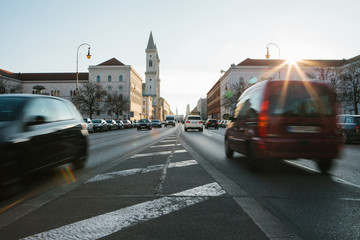 Fototapeta na wymiar View of the road on the street Leopoldstrasse in Munich - the capital of Bavaria in Germany. Fast blurred motion car on sunset background.