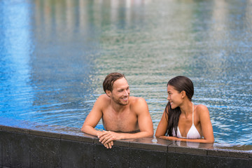 Fototapeta premium Pool couple relaxing on luxury resort travel holiday swimming in infinity pool at tropical villa hotel.