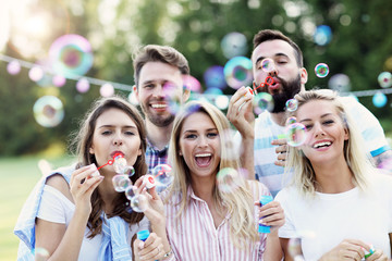 Happy group of friends blowing bubbles outdoors