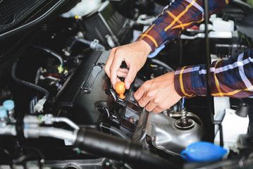 Obraz premium Close up hands checking lube oil level of car engine from deep-stick for service and maintenance concept