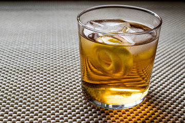 Highball cocktail with lemon peel and ice.