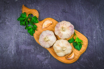 Garlic cloves and garlic bulb on a wooden board on a gray background.