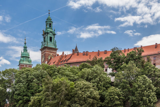 a view of Wawel castle surrounded by trees with blue sky on a summer day