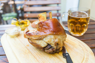 eisbein with bread, vegetables and beer on wooden cutting board