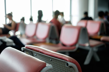 Blur background of people waiting at airport. blinding backlight from window, with empty chair seat in airport hall / lounge. Concept of lifestyle, tourism, holiday, travel.