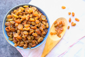 A raisin in the blue bowl . Wooden spoon.