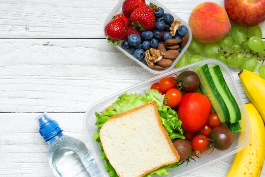 School lunch boxes with sandwich, fruits, vegetables and bottle of water and copy space