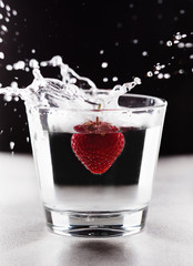 Strawberry splashing into glass of water