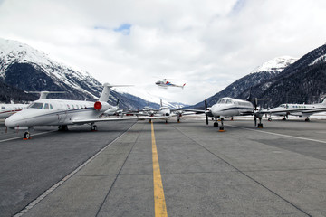 Fototapeta na wymiar Private jets and a helicopter in St Moritz